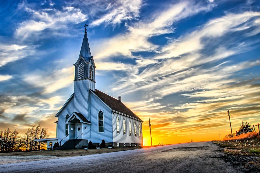 A wooden church at dusk with sunset clouds.