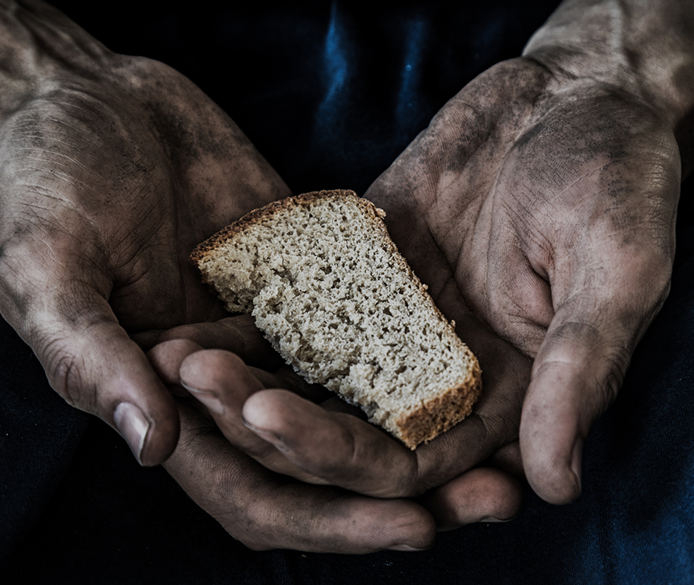 Hands holding a small piece of bread, representing hunger and the urgent need to support the food insecure through CityServe’s Compassion Initiatives.