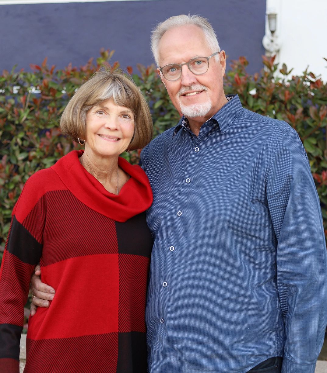 Terry and Mary Inman, CityServe board members, smiling outdoors near a green hedge.