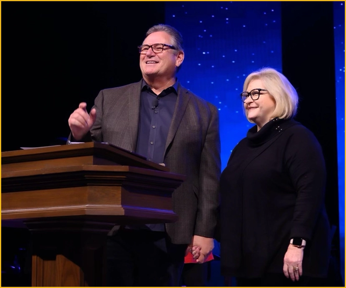 Wendell and Lynda Vinson standing on stage together, holding hands and smiling while addressing the audience at Canyon Hills Church.
